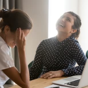 Two women laughing in front of computer